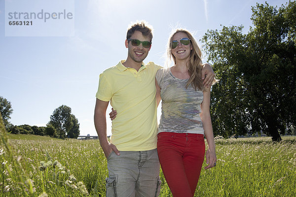 Germany  North Rhine Westphalia  Duesseldorf  Couple walking in grass  smiling