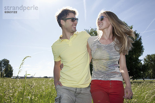 Germany  North Rhine Westphalia  Duesseldorf  Couple walking in grass  smiling