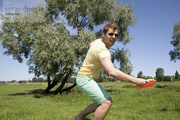Germany  North Rhine Westphalia  Duesseldorf  Mid adult man playing with frisbee  smiling