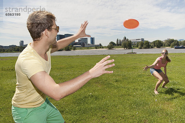 Germany  North Rhine Westphalia  Duesseldorf  Couple playing with frisbee