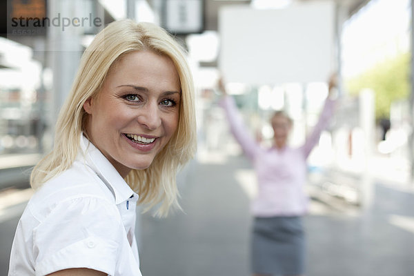 Geschäftsfrau lächelnd  eine andere Frau mit Plakat im Hintergrund
