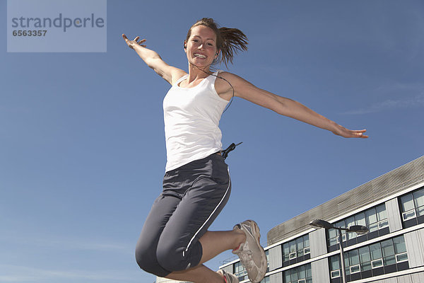 Junge Frau springt in die Luft  lächelnd  Portrait