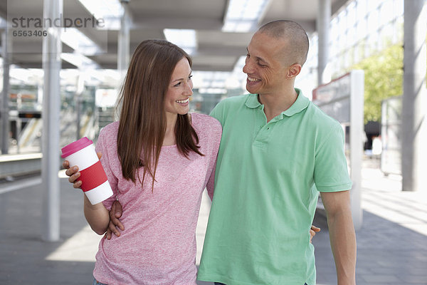 Ein junges Paar läuft  während eine Frau einen Becher hält.