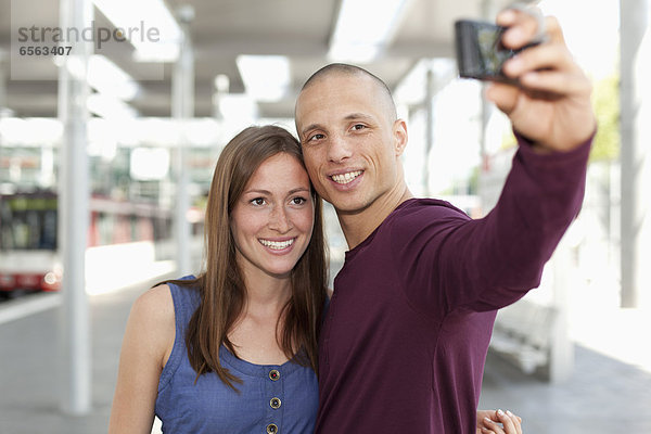 Germany  North-Rhine-Westphalia  Duesseldorf  Young couple photographing self with smart phone