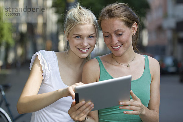 Germany  North Rhine Westphalia  Cologne  Young women using digital tablet  smiling