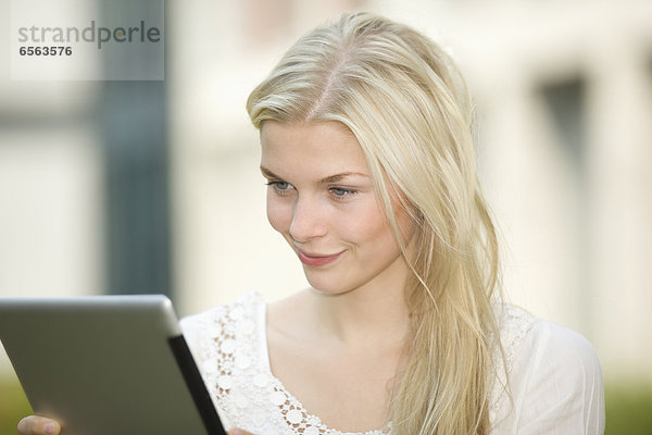 Germany  North Rhine Westphalia  Cologne  Young student with digital tablet  smiling
