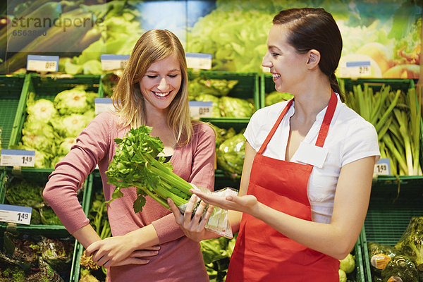 Young womens with celery in supermarket
