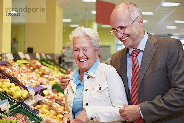 Germany  Cologne  Mature couple in supermarket  smiling