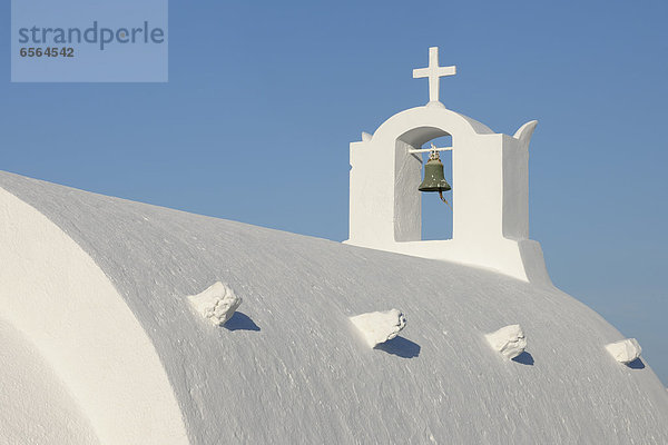 Griechenland  Weißgetünchte traditionell griechische Kirche mit Glockenturm und Kreuz in Oia bei Santorini