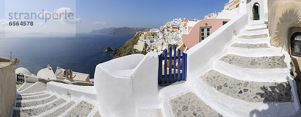 Griechenland  Blick auf das Dorf Oia mit Kopfsteinpflasterweg und blauem Tor bei Santorini