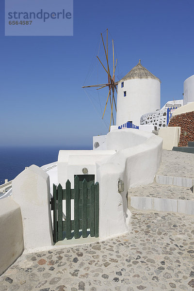 Greece  Windmill with cobbled path and green gate in traditionally Greek village Oia at Santorini