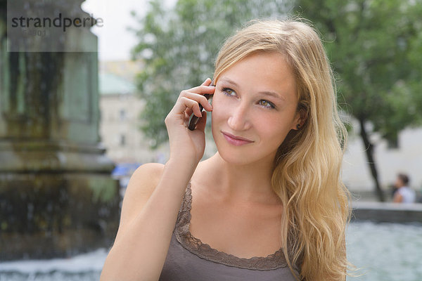 Young woman talking on phone in front of Ludwig Maximilian University