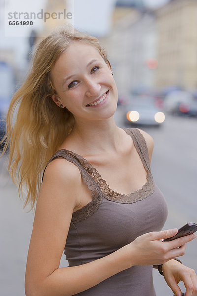 Young woman with smart phone in front ofn State Library at Ludwigstrasse