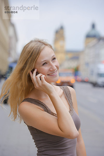 Junge Frau mit Smartphone vor der Staatsbibliothek in der Ludwigstraße
