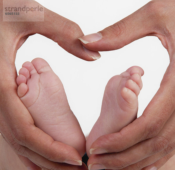 Mutter hält Babys Fuß mit Herzform  Nahaufnahme