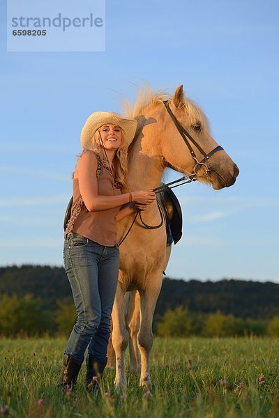 Lächelnde Frau mit Pferd auf einer Wiese