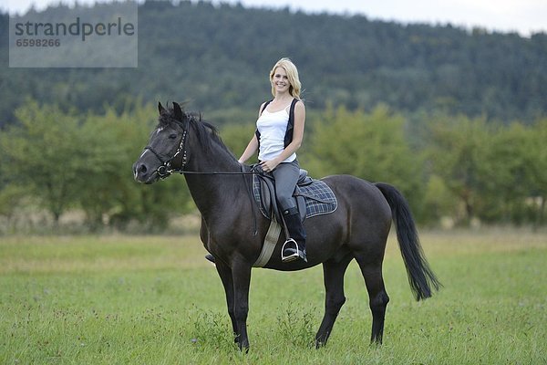 Lächelnde Frau sitzt auf einem Pferd