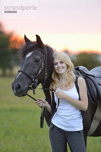 Lächelnde Frau mit Pferd auf einer Wiese