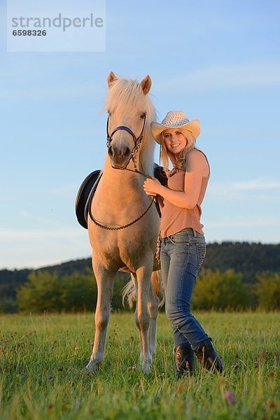 Lächelnde Frau mit Pferd auf einer Wiese