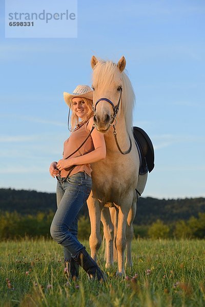 Lächelnde Frau mit Pferd auf einer Wiese