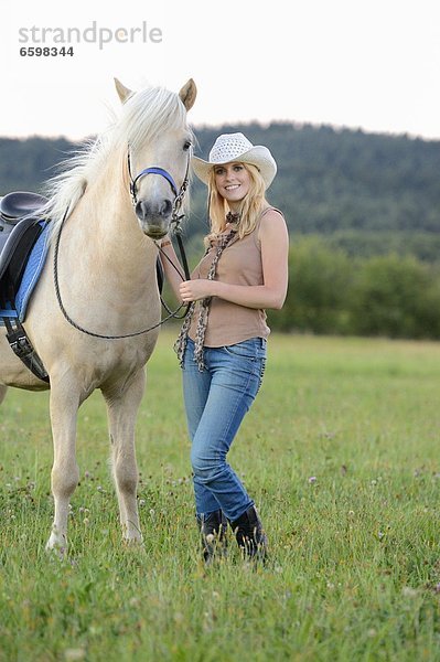 Lächelnde Frau mit Pferd auf einer Wiese