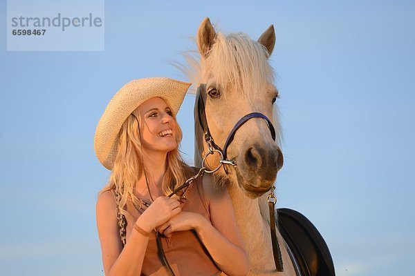 Lächelnde Frau mit Pferd unter blauem Himmel