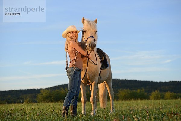 Lächelnde Frau mit Pferd auf einer Wiese