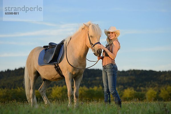 Lächelnde Frau mit Pferd auf einer Wiese