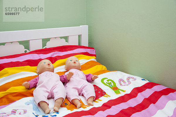 Zwei Puppen auf einem Kinderbett