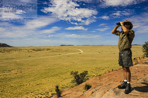Mann schaut durch Fernglas ins Damaraland  Namibia  Afrika
