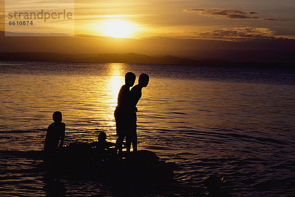 Felsbrocken  Junge - Person  Sonnenuntergang  Silhouette  See