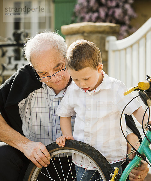 Europäer  Enkelsohn  Großvater  Fahrrad  Rad  reparieren