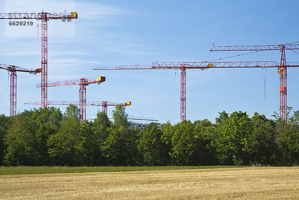 Kräne auf einer Baustelle an einem Feld