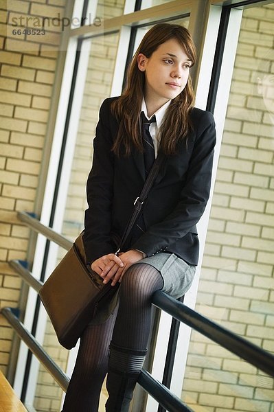A Student In Uniform  Seated On Railing