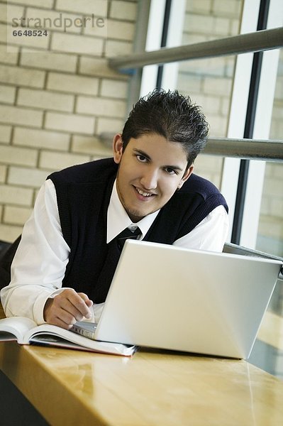 A Student In Uniform  Working On A Laptop