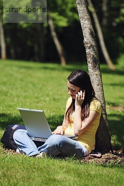 Handy  Jugendlicher  sprechen  Notebook  Baum  arbeiten  unterhalb  Mädchen