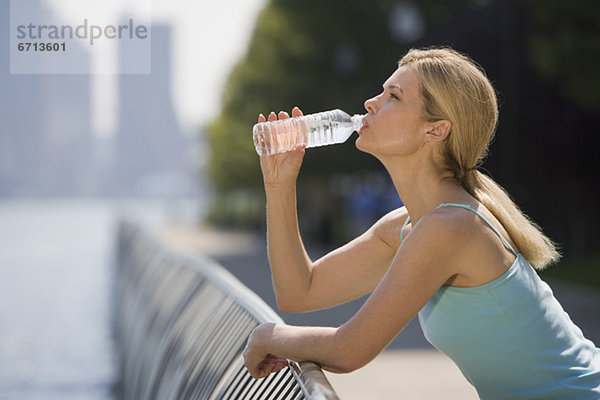 Frau trinkt aus Wasserflasche im Freien
