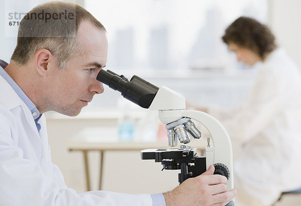 Männlicher Wissenschaftler schauen hinein Mikroskop