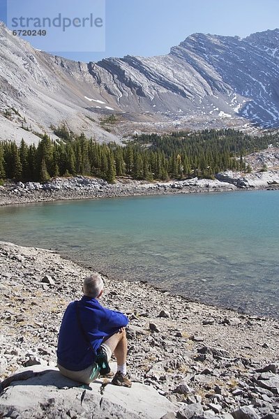 sitzend  nebeneinander  neben  Seite an Seite  Berg  Mann  See