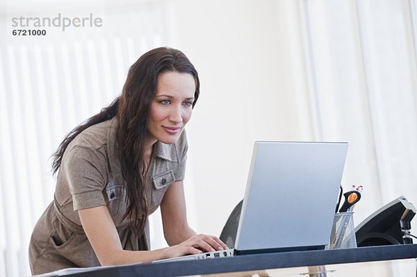 Frau mit Computer im Büro  lächelnd