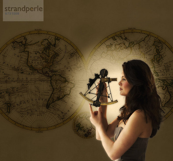 Woman looking through antique sextant  world map in background