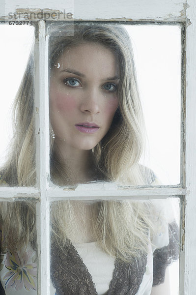 Portrait einer jungen Frau looking durch Fenster