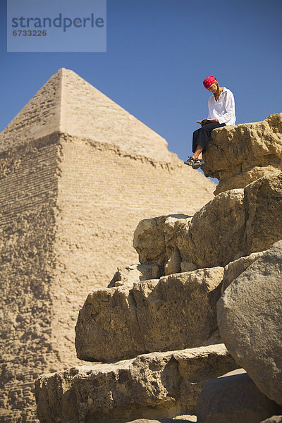 pyramidenförmig  Pyramide  Pyramiden  Kairo  Hauptstadt  nahe  sitzend  Führung  Anleitung führen  führt  führend  lesen  Buch  Tourist  frontal  Taschenbuch  Gise