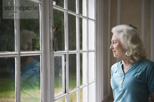 ältere Frau looking durch Fenster