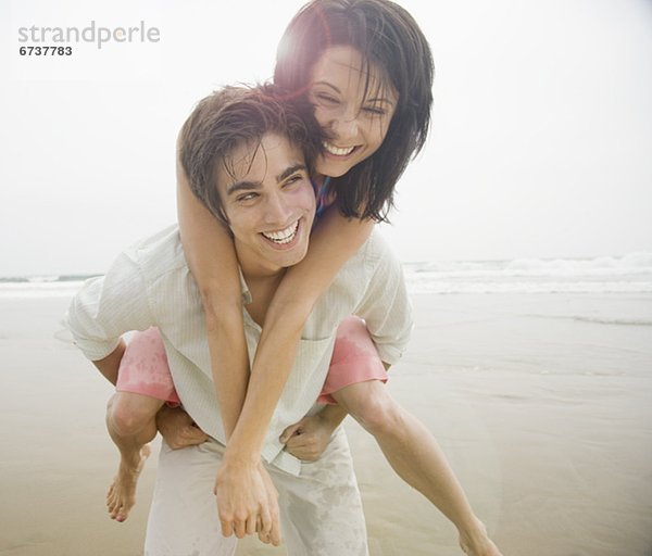 Mann mit Frau piggyback ritt am Strand