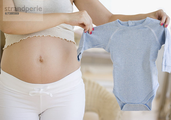 Pregnant Frau hält Baby-Kleidung