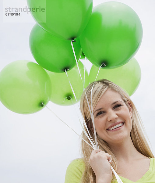 Portrait of junge Frau hält grün Ballons