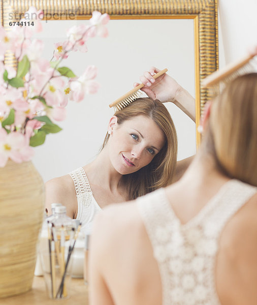 Junge Frau Haare an Spiegel Bürsten