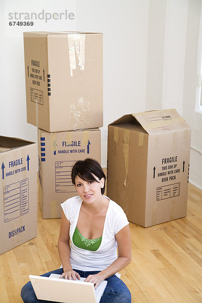 Female on Floor with Laptop  Moving Boxes behind her