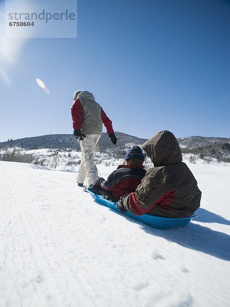 Vater zieht Kinder auf Schlitten durch den Schnee  fully_released